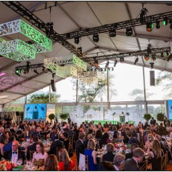 Large crowd inside a tent under colorful lights