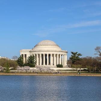 Large white stone building with columns near water